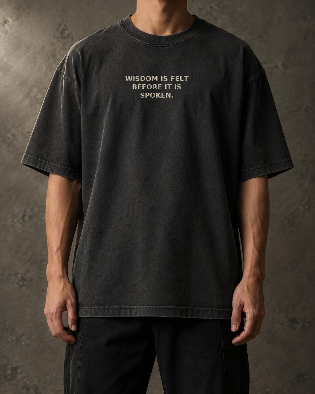 Washed black t-shirts front with the embroidered quote “Wisdom is felt before it is spoken.”